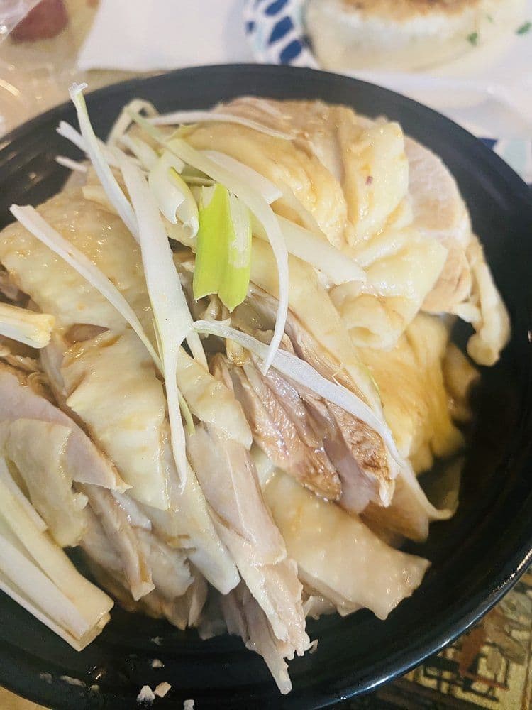 Hainan Chicken (海南鸡) — Tender poached chicken served with fragrant rice, ginger-scallion sauce, and savory broth.